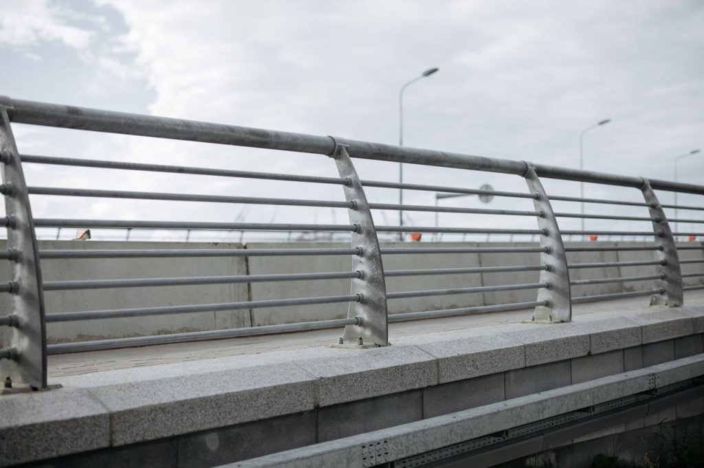 A modern bridge featuring concrete and metal railings under a cloudy sky.
