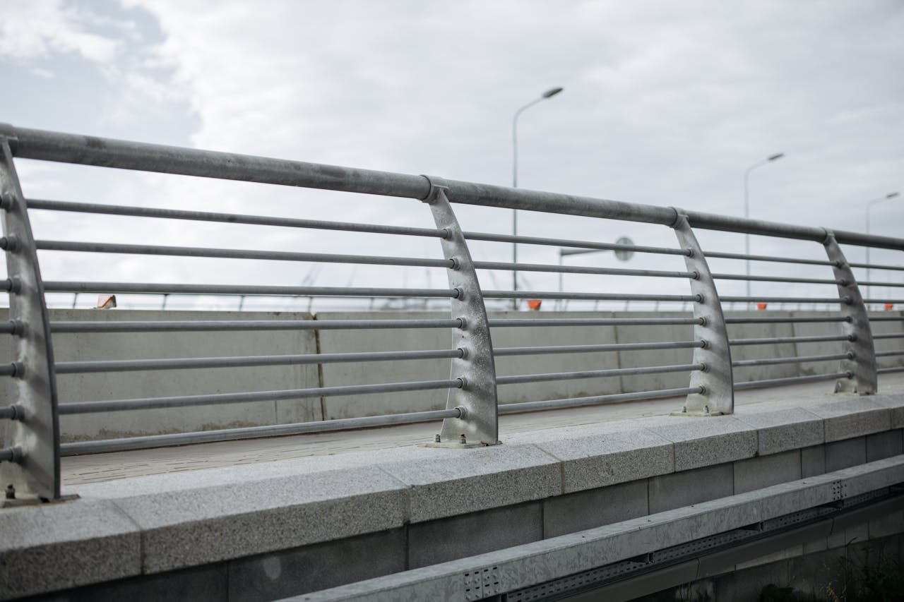 A modern bridge featuring concrete and metal railings under a cloudy sky.